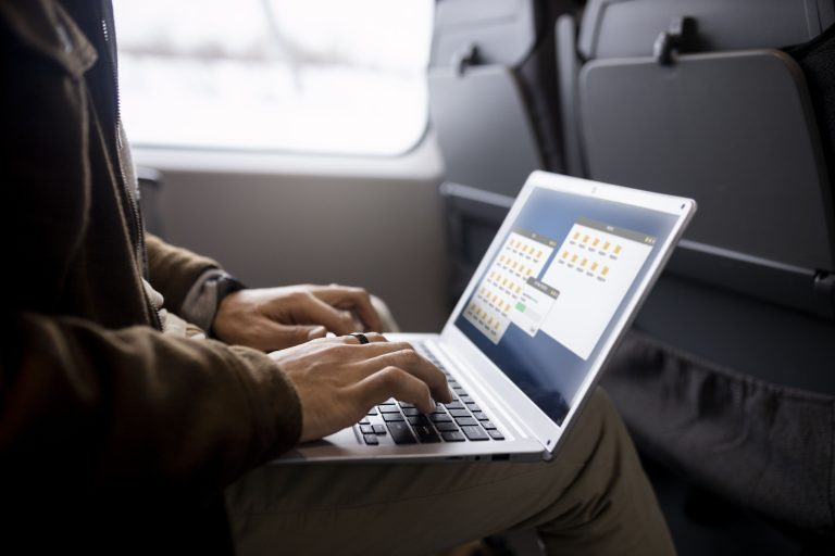 Uma pessoa usando um laptop dentro de um veículo.